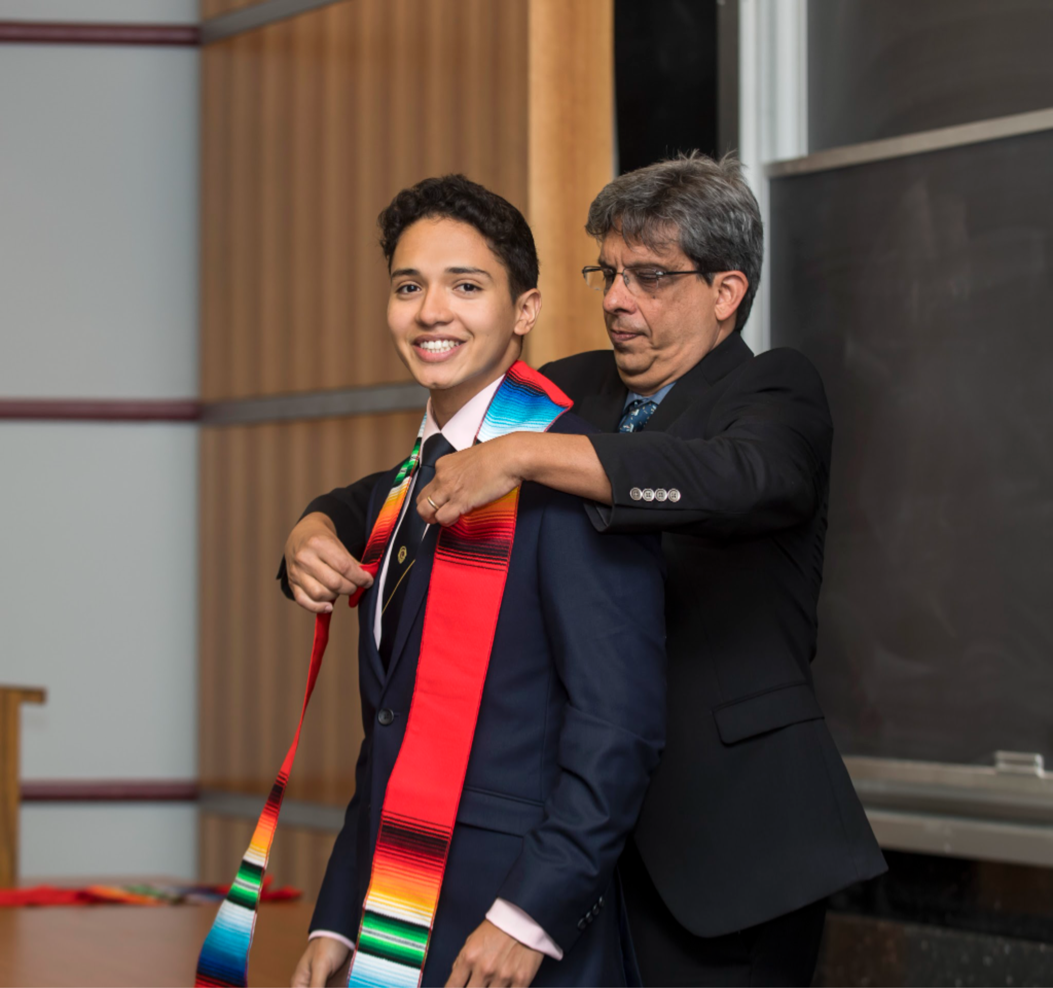 Prof. Jose Aranda presenting sarape to graduating senior at SOLAR ceremony